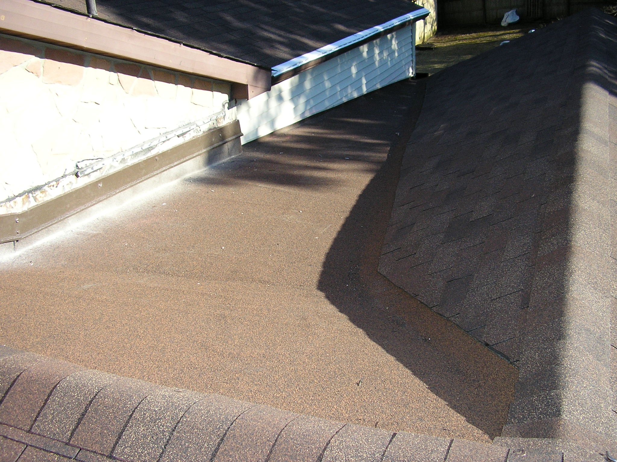 Newly installed brown asphalt shingles on a roof section.
