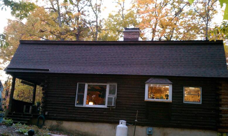 Cozy cabin with warm lights glowing through windows in autumn.